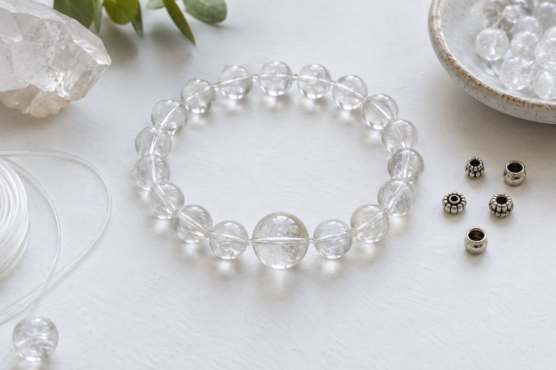Clear beads laid out as a bracelet with one larger bead at the center and spacer beads set aside.