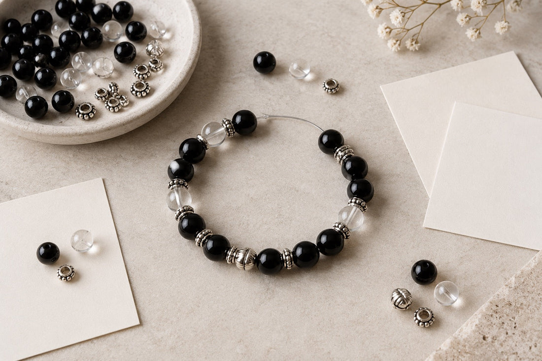 Black, silver-tone and clear beads arranged as a custom bracelet layout study.